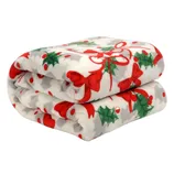 A plush, white blanket featuring a festive pattern with red bows, green holly leaves, and red berries, ideal for holiday-themed decor.