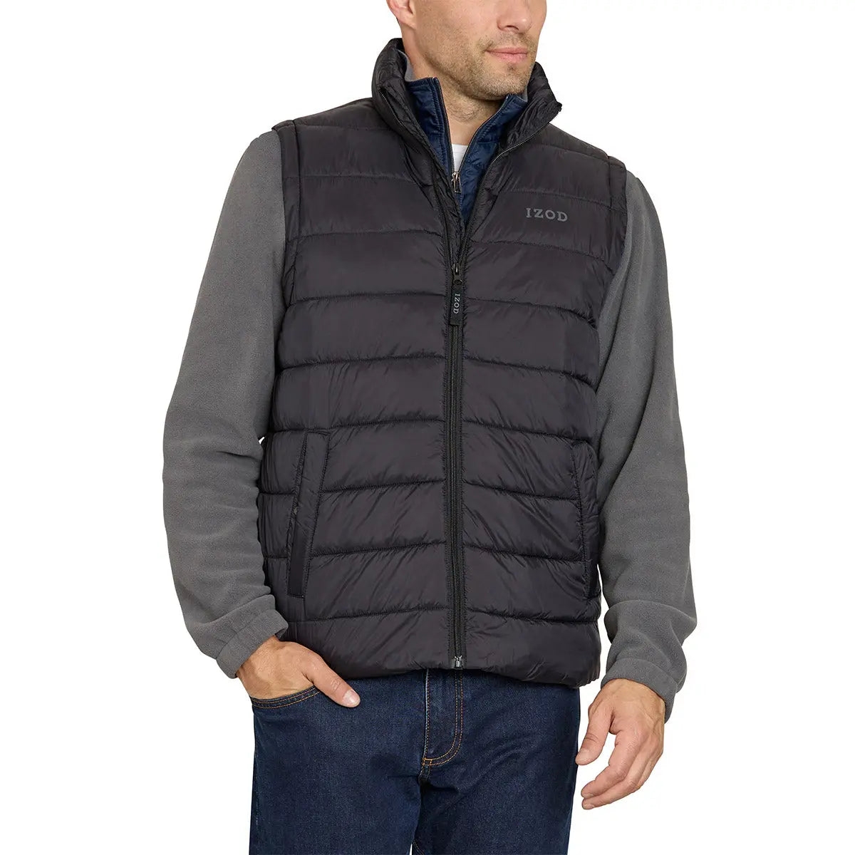 A man is wearing a dark gray Izod puffer vest over a gray long-sleeve shirt, paired with blue jeans. The vest has a zippered front and the Izod logo on the left chest.
