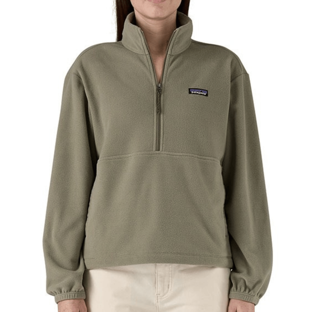 A light olive-green fleece quarter-zip pullover with a Patagonia logo on the left chest, paired with light beige pants.