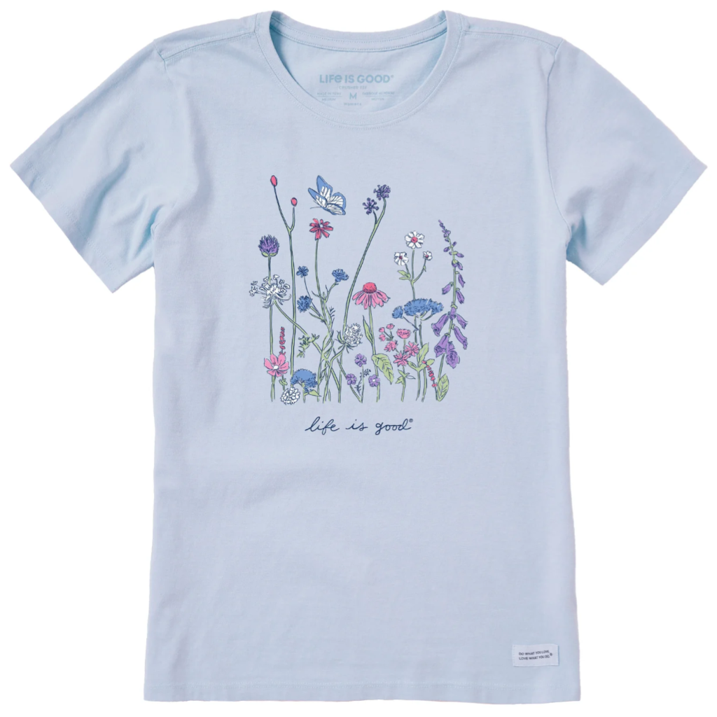 Light blue T-shirt with a floral and butterfly design, featuring various pastel-colored flowers. The phrase \“life is good\“ is written below the illustration.