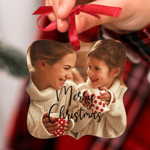 A Christmas ornament features two people in cozy sweaters, smiling and holding red polka dot mugs, with \“Merry Christmas\“ written on it.
