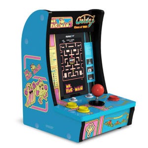 A compact arcade machine features Ms. Pac-Man, Galaga, and Galaxian games, with classic joystick and button controls, vibrant blue sides, and retro artwork.