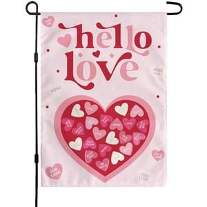 A garden flag with \“hello love\“ and various heart-shaped candies featuring phrases like \“XOXO\“ and \“MISS YOU\“ on a pink background, designed for Valentine's Day.