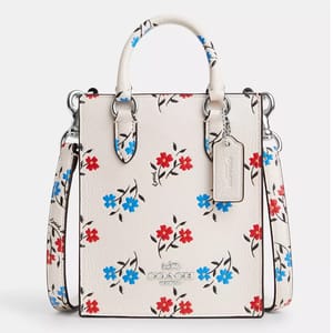 White handbag with floral print and a brand logo tag attached to the handle.