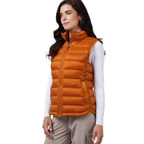 A woman is wearing a sleeveless, orange packable vest with a zip-up front and a high collar. The vest has a quilted design and side pockets.