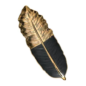 A decorative leaf-shaped tray with a gold and black design.