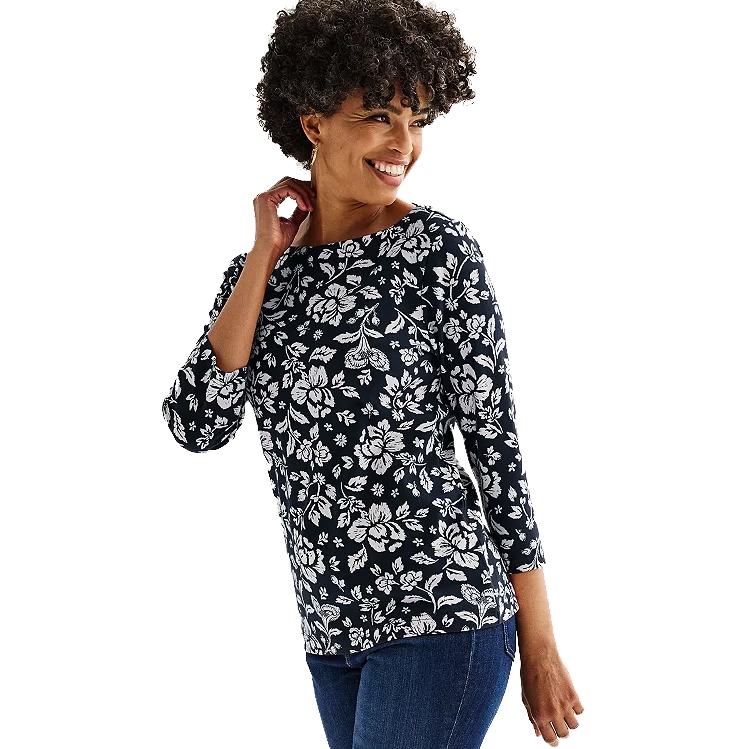 Woman wearing a Croft & Barrow boatneck top with a navy blue and white floral pattern, featuring three-quarter sleeves. She pairs it with blue jeans, showcasing a casual and stylish look.