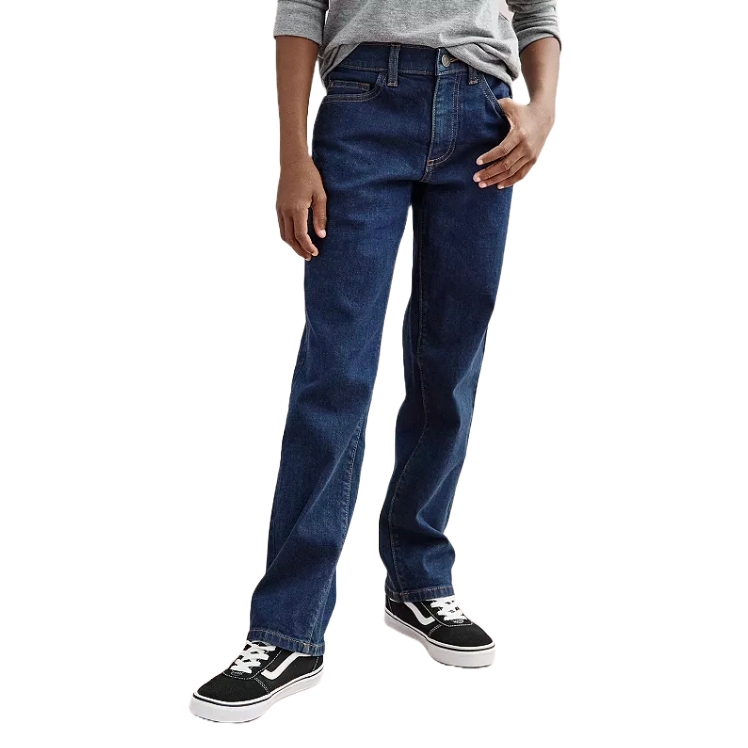 A person wearing dark blue straight-leg jeans paired with black and white sneakers and a gray long-sleeve shirt.