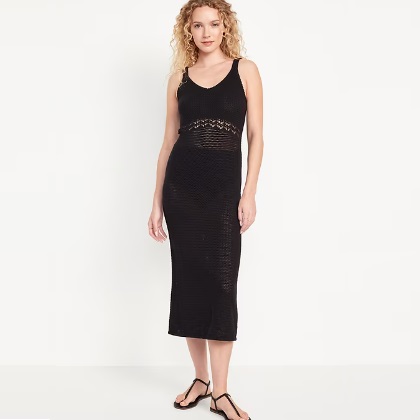 A woman models a black sleeveless midi dress with crochet detailing and strappy sandals.