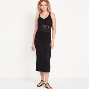A woman models a black sleeveless midi dress with crochet detailing and strappy sandals.