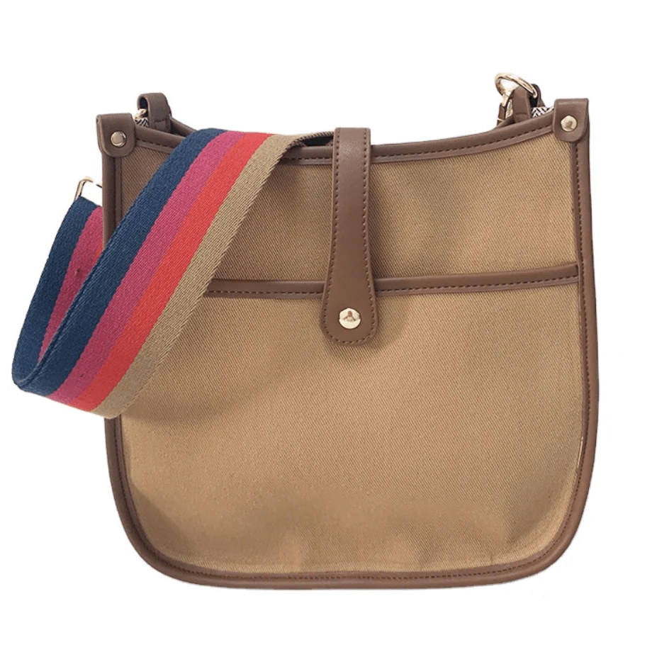 Brown canvas courier bag with leather trim and a colorful adjustable strap featuring tan, red, and blue stripes. It has a front pocket and a simple button closure.