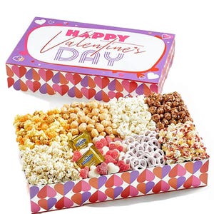 Valentine's Day box featuring caramel, cheddar, and chocolate-drizzled popcorn varieties, yogurt-covered pretzels, heart-shaped gummies, and Ghirardelli chocolates, with a festive heart-themed design.