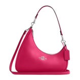 A bright pink Coach shoulder bag with a curved design, detachable strap, and silver hardware. The logo is prominently displayed on the front.
