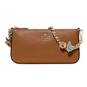 A brown leather Kate Spade shoulder bag features a decorative strap with floral accents, providing a stylish and elegant accessory option.