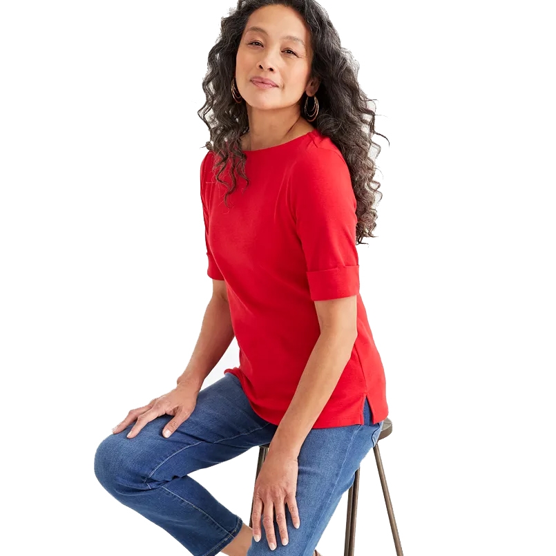 A woman is wearing a red elbow-sleeve top with a boat neckline, paired with blue jeans.