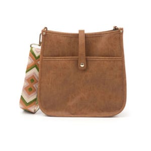 Brown courier bag with a fold-over strap and button closure, featuring a detachable multicolored woven guitar strap with geometric patterns.