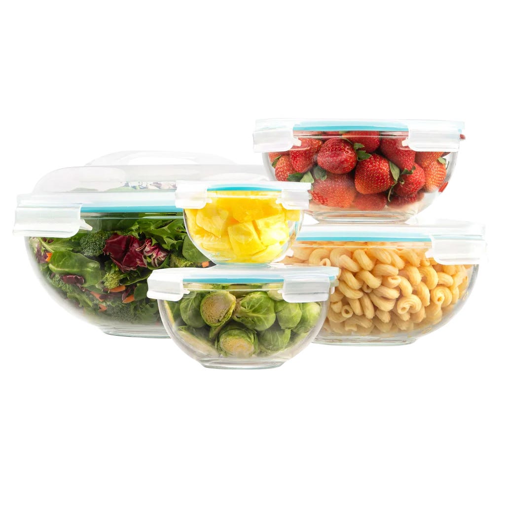 5-piece glass bowl set with clear, airtight lids, containing salad, strawberries, pineapple chunks, Brussels sprouts, and pasta. Each bowl is transparent, showcasing its contents, with secure lid locks, ideal for food storage and freshness.