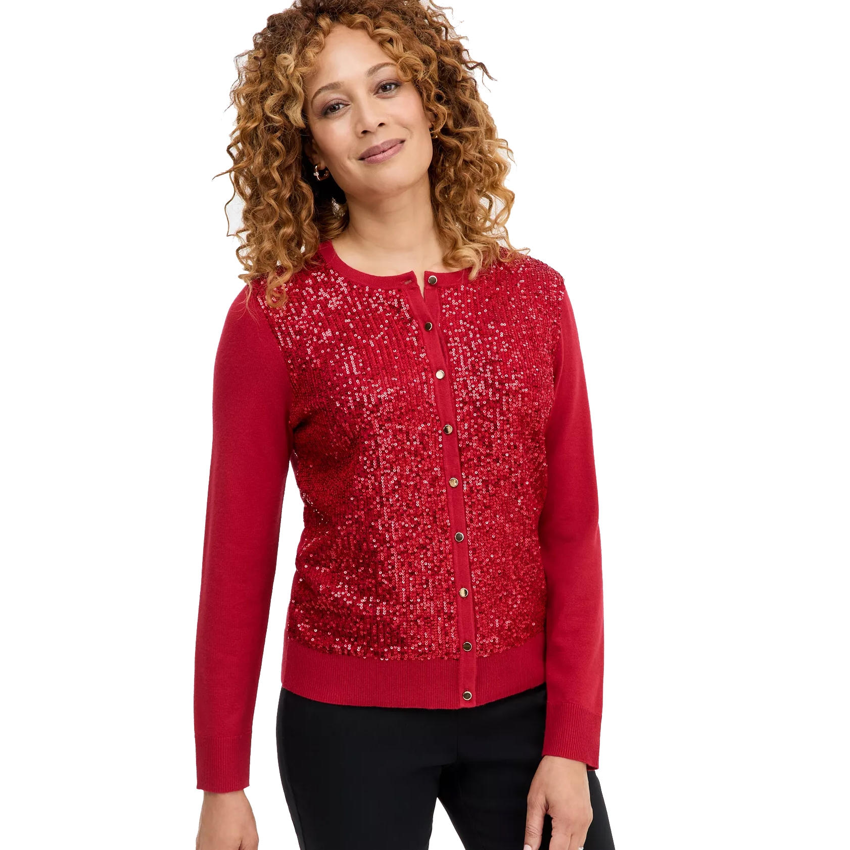 A woman is wearing a red cardigan adorned with sequins, featuring a button-up front. Her curly hair frames her face, and she is paired with black pants.