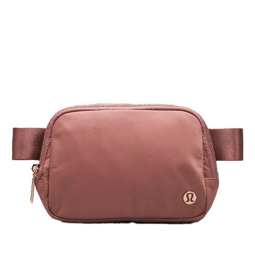 A small, brown belt bag with a simple design and metal zipper hardware, featuring a logo in the bottom right corner.