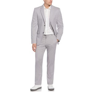 A man is wearing a light gray suit with a white shirt and white sneakers. The outfit has a modern, casual vibe suitable for semi-formal occasions.