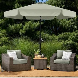 Outdoor patio set with two wicker chairs featuring green cushions, a small side table, and a beige umbrella, set on a beige rug against a backdrop of lush greenery.