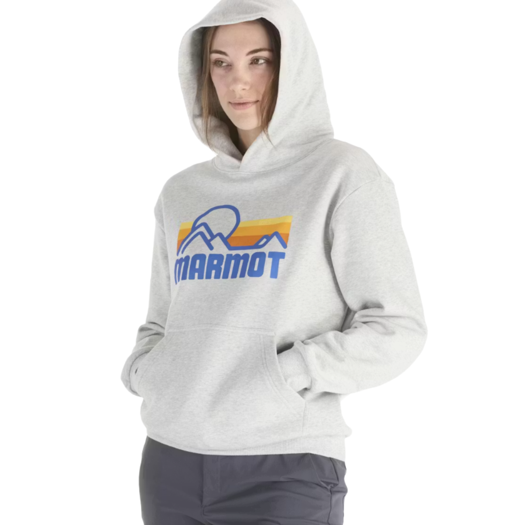 A person is wearing a gray hooded sweatshirt with a \“MARMOT\“ logo featuring mountains and a sunrise design, along with dark pants.
