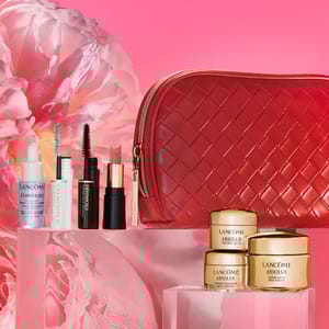 Lancôme beauty set featuring skincare items, mascara, lipstick, and a red textured cosmetic bag, displayed on a pink floral background.