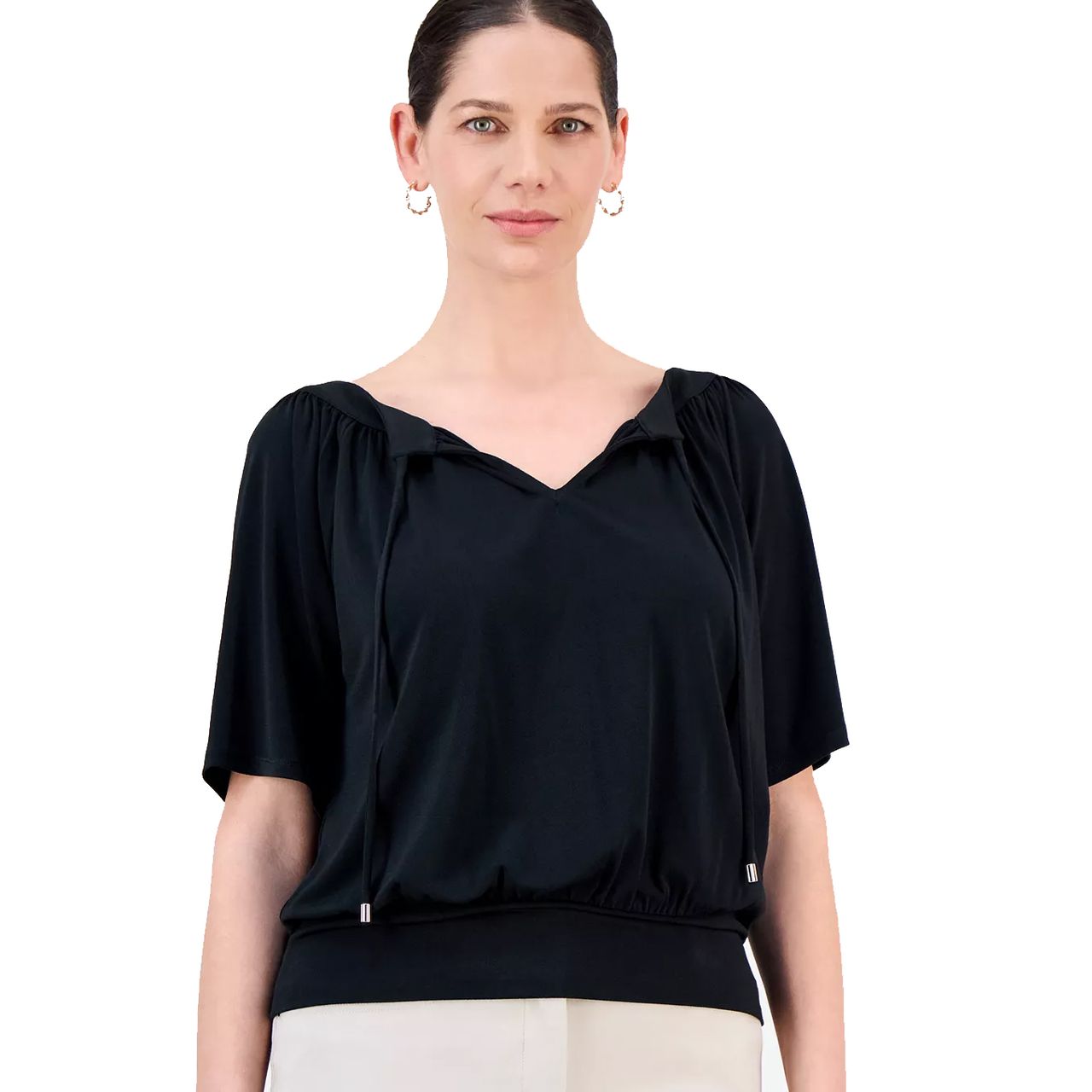 A woman is wearing a black short-sleeve top with a gathered neckline and drawstrings, paired with light-colored pants.