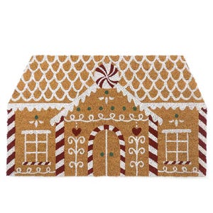A doormat designed to resemble a gingerbread house, featuring decorative white icing patterns and red stripes.