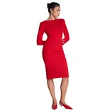 A person is wearing a fitted red knee-length dress with long sleeves, paired with red pointed-toe heels, and accessorized with large silver hoop earrings.
