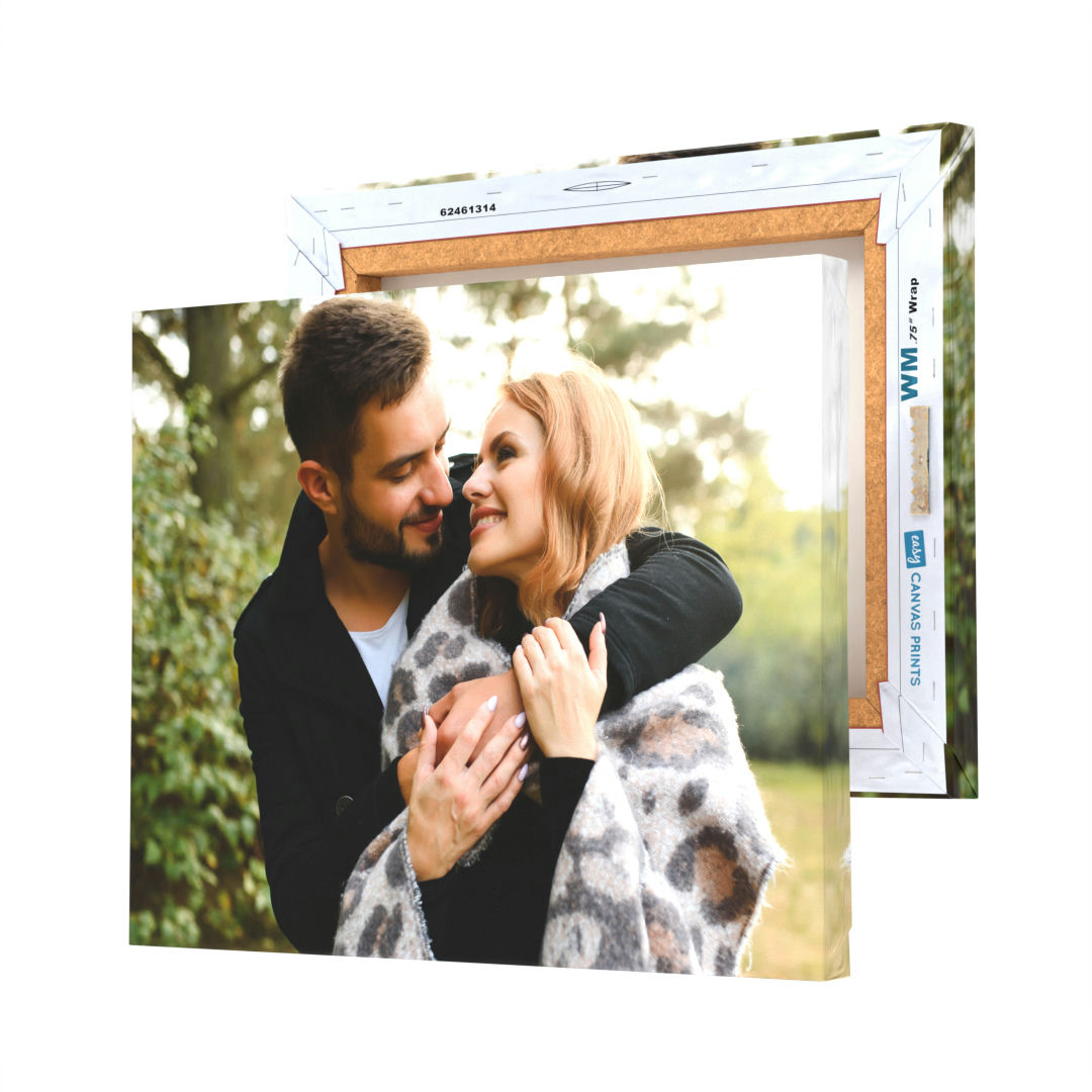 An 11\“ x 14\“ canvas print displays a photo of a smiling couple embracing, framed by an outer cardboard edging to suggest a frame or packaging.
