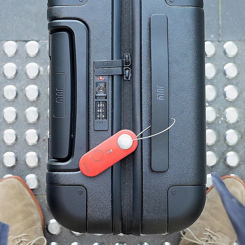 A black hard-shell suitcase with a combination lock and an attached red luggage tag.