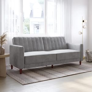 A modern gray fabric sofa with tufted backrest and wooden legs is set in a bright room near a large window, complemented by a floor lamp and a round table with decorative elements.