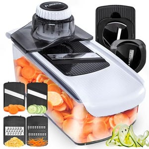 A mandoline slicer with interchangeable blades for slicing, grating, and julienning vegetables, housed in a white and black container.