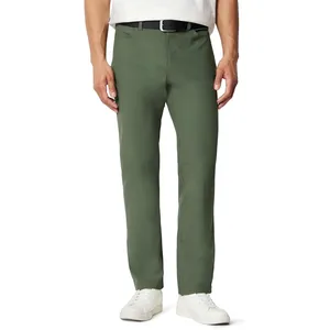 A man is wearing green chinos with a black belt and white sneakers, paired with a white shirt.