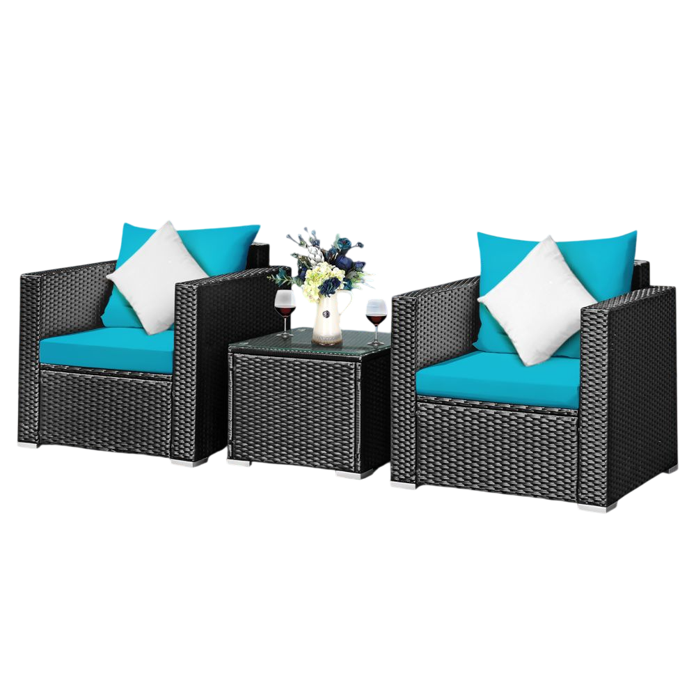 Outdoor patio furniture set with two wicker chairs and a glass-top table. Features turquoise cushions, white pillows, and holds two wine glasses and a flower vase. Set is placed on a wooden deck beside a pool.