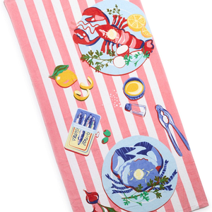 A towel with a pink and white striped pattern, featuring illustrations of a lobster, crab, lemon slices, herbs, a yellow sauce bowl, salt shaker, nutcracker, orange slice, matches, and sunglasses.