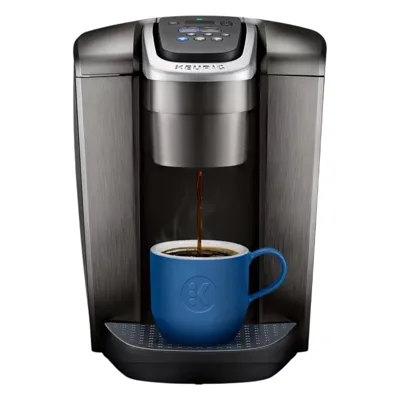 A Keurig coffee maker is brewing coffee into a blue cup placed on its drip tray.