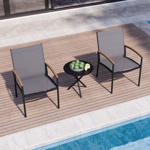 Two sling-style patio chairs with wooden armrests and a small round table, set on an outdoor deck by a pool.