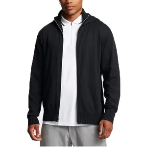 A person wears a black zip-up hoodie over a white polo shirt and light gray pants.