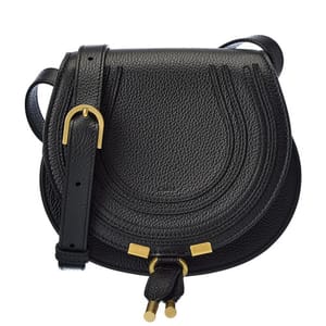 The Chloe Marcie Saddle Bag is a black, textured leather crossbody bag featuring a curved flap with stitched detailing and gold-tone hardware accents, including two dangling tassels.