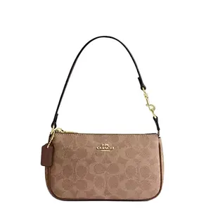 A Coach wristlet in light brown with the signature \“C\“ pattern and gold-tone hardware, featuring a detachable strap and a small tag.