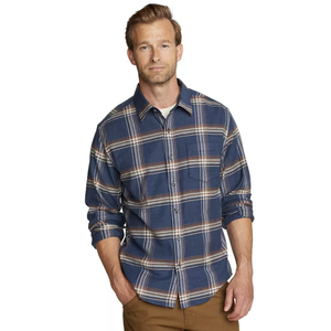 A man wears a blue plaid button-up shirt paired with brown pants.