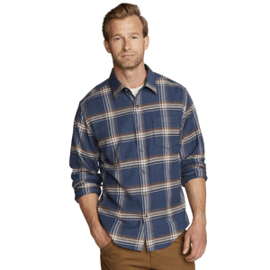 A man wears a blue plaid button-up shirt paired with brown pants.
