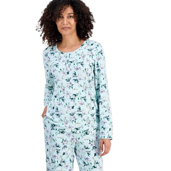 A woman is wearing light blue floral-patterned pajamas with long sleeves and matching pants.