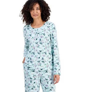A woman is wearing light blue floral-patterned pajamas with long sleeves and matching pants.