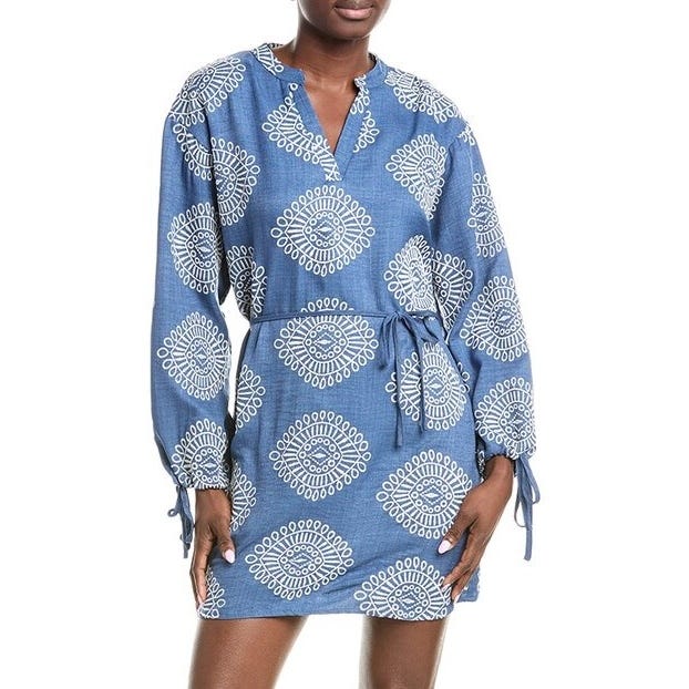 Blue dress with white geometric patterns, featuring long sleeves and a tied waist belt.
