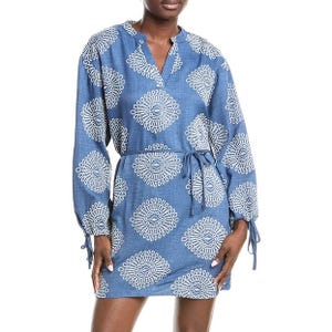 Blue dress with white geometric patterns, featuring long sleeves and a tied waist belt.