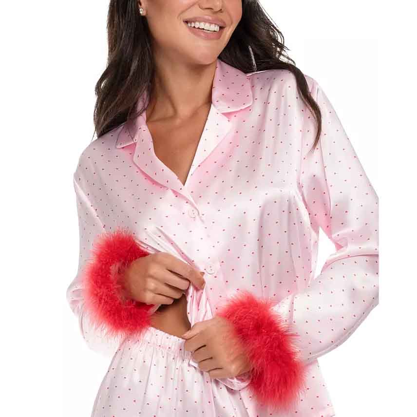 A pink satin pajama set with small polka dots, featuring long sleeves and vibrant red faux-fur trim on the cuffs.