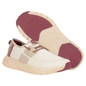 Hey Dude Women's Sirocco Shoes feature a cream and red color scheme with a textured sole for grip. They have a mesh upper for breathability, speckled midsole, and lace-up closure for a secure fit.